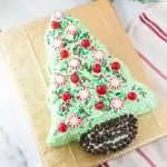 christmas tree shaped cake decorated with peppermints, sprinkles, and chocolate chips