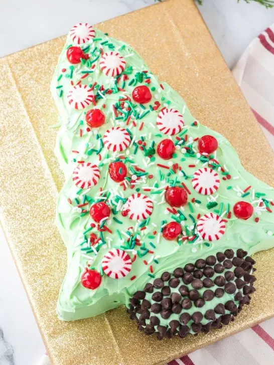 christmas tree shaped cake decorated with peppermints, sprinkles, and chocolate chips