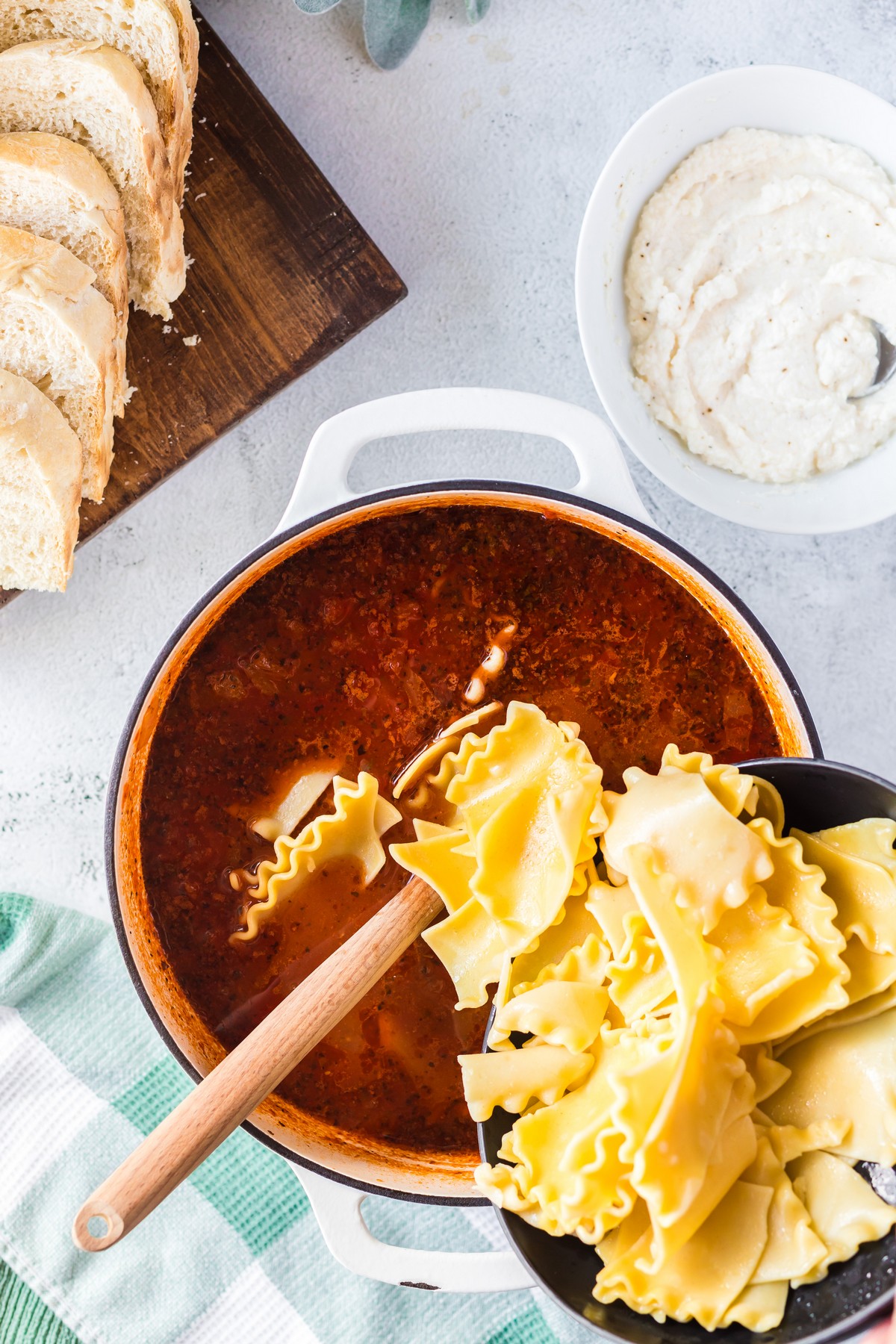 adding uncooked lasagne noodles to a pot of lasagna soup