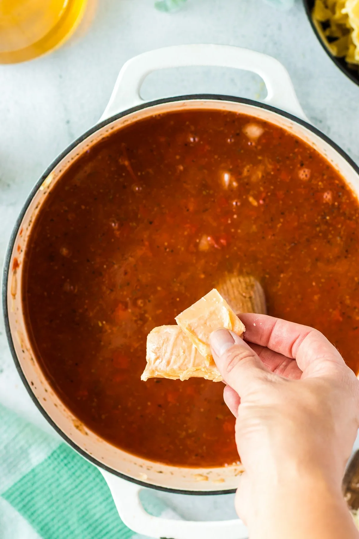 adding parmesan rinds to a pot of lasagna soup