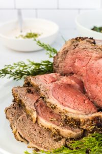 sliced prime rib roast on a white serving platter