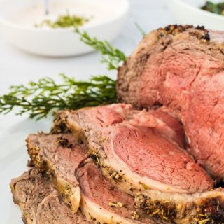 sliced prime rib roast on a white serving platter