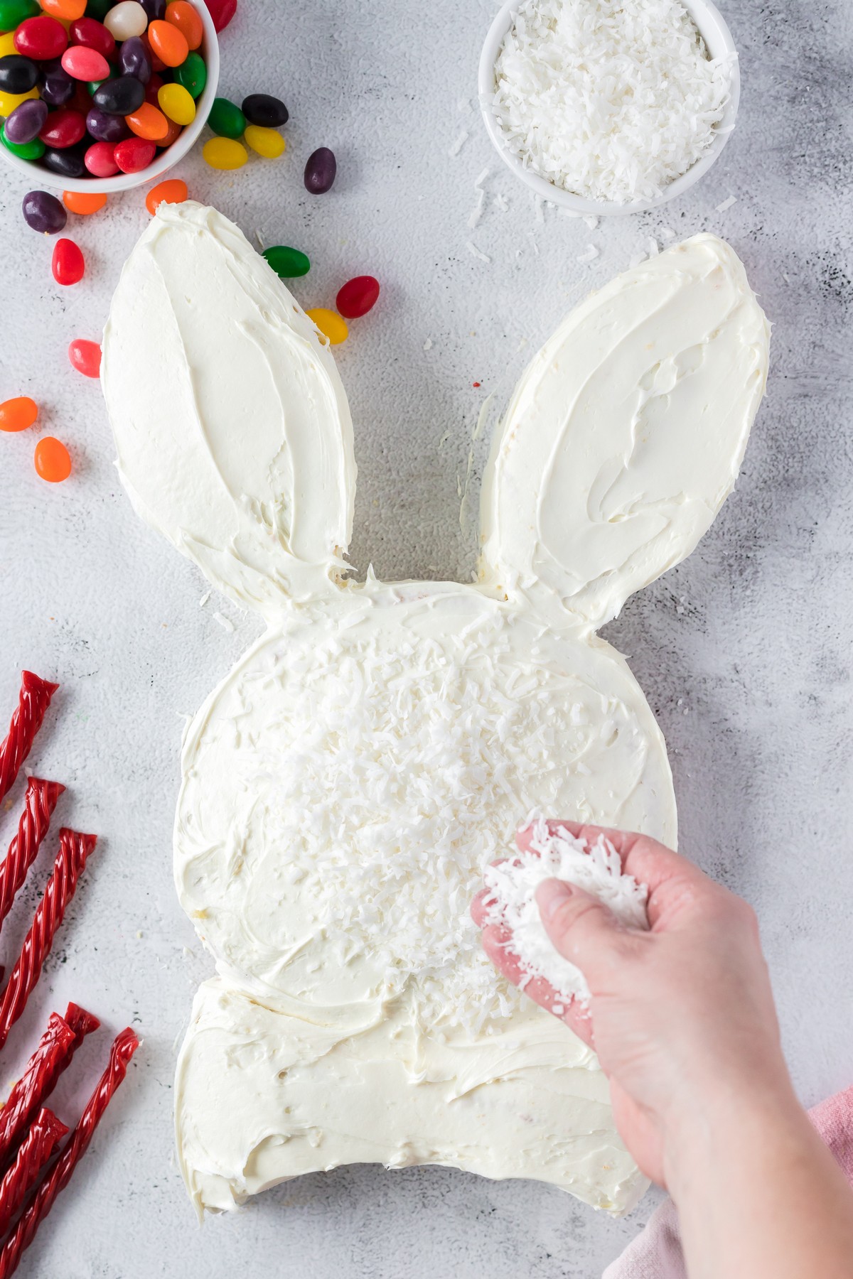 sprinkling coconut over easter bunny cake