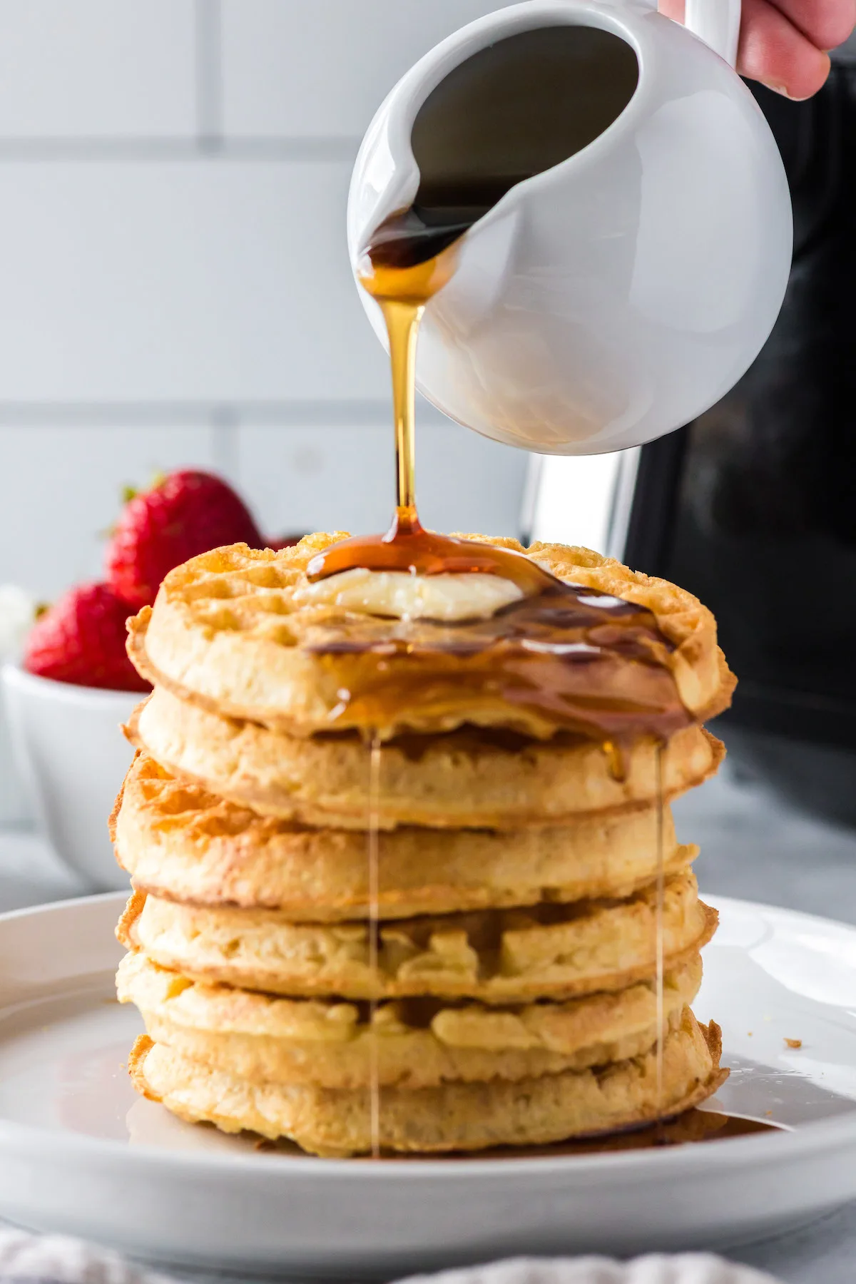 pouring syrup on waffle stack