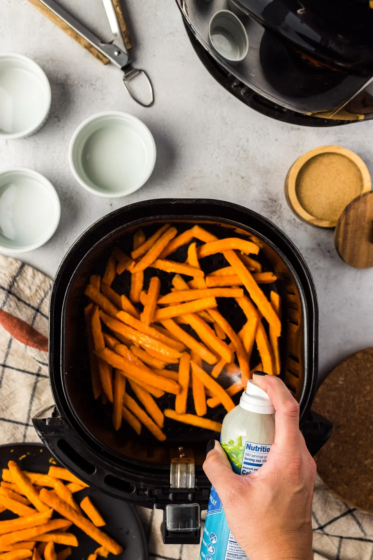 spraying olive oil spray on sweet potato fries