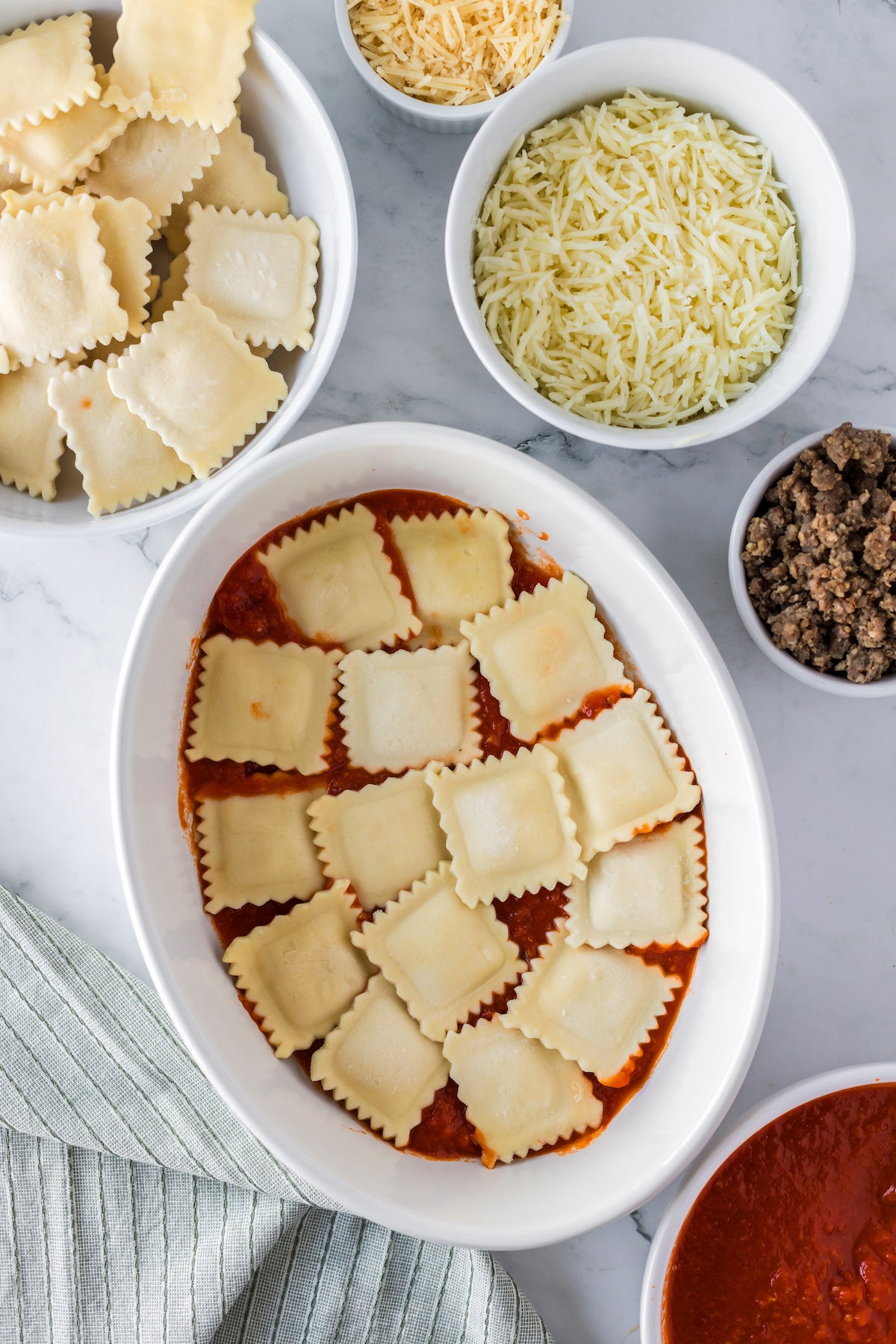 layering baked ravioli casserole ingredients