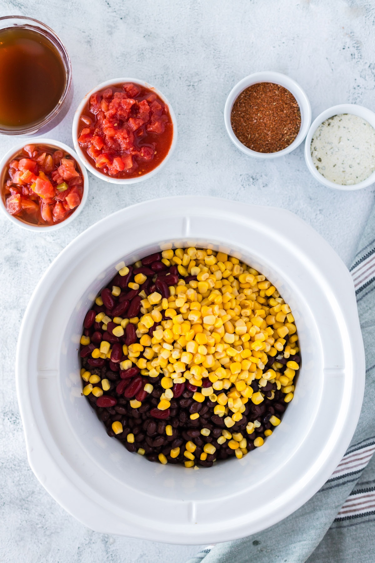 adding corn, beans, and ground beef to crock pot
