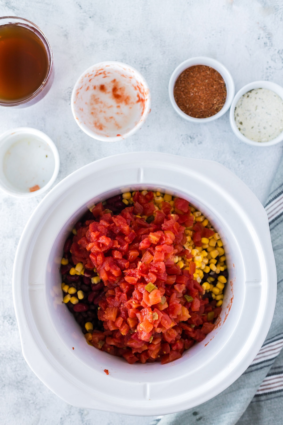 adding corn, beans, tomatoes and ground beef to crock pot