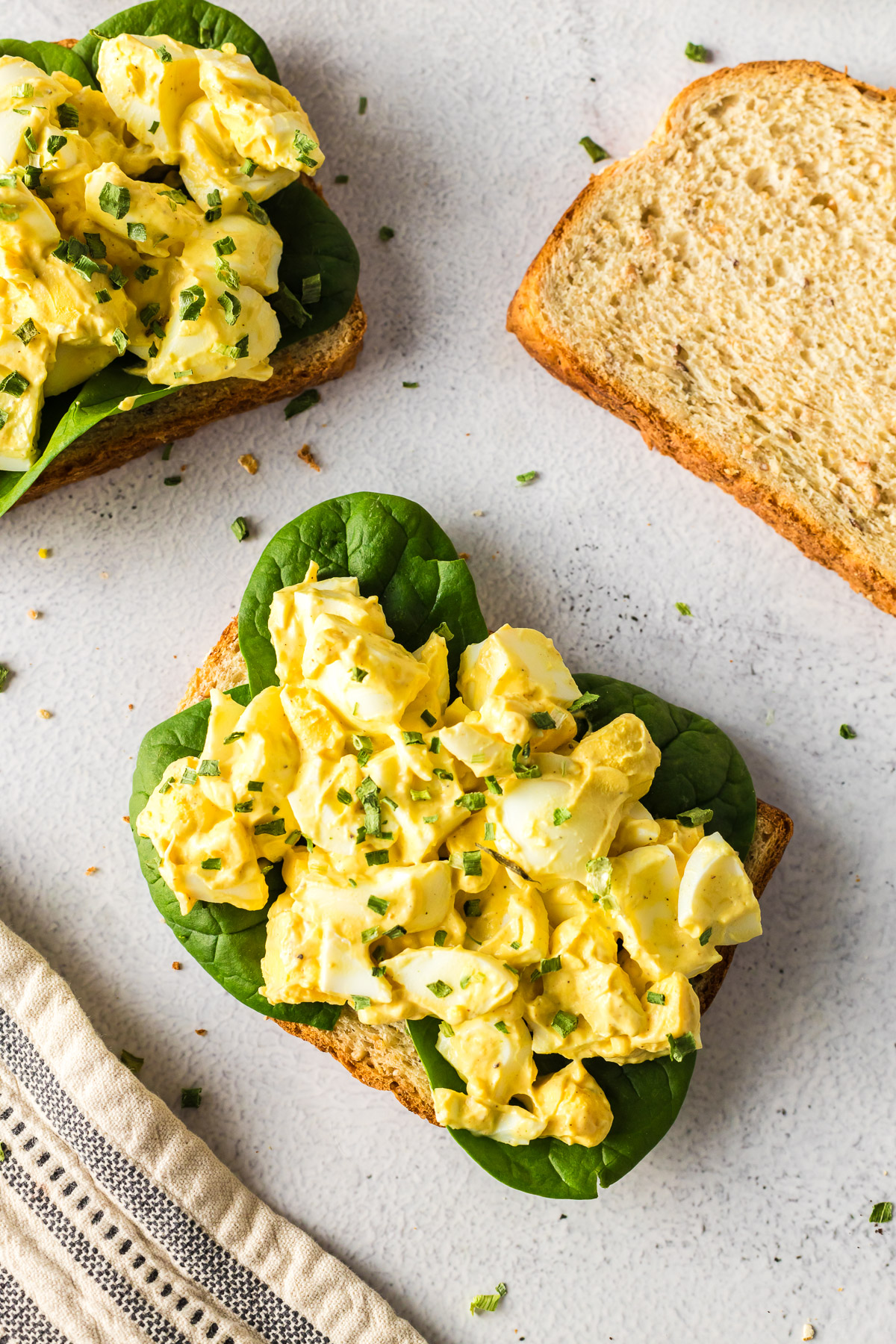 egg salad on wheat bread with spinach leaves