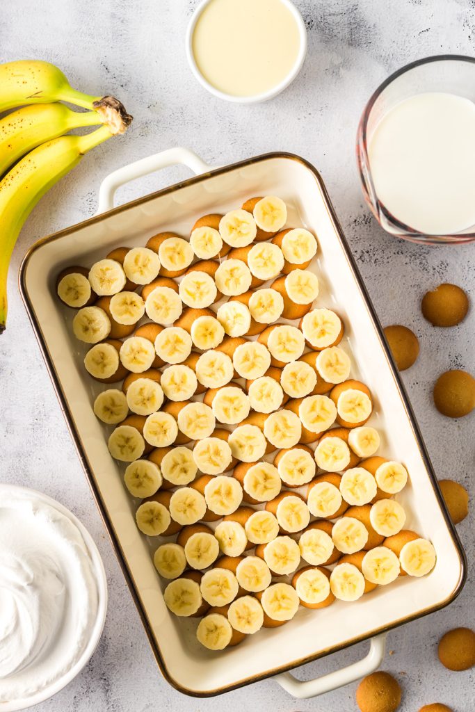 banana slices and Nilla wafers in the bottom of a deep dish casserole dish for banana pudding