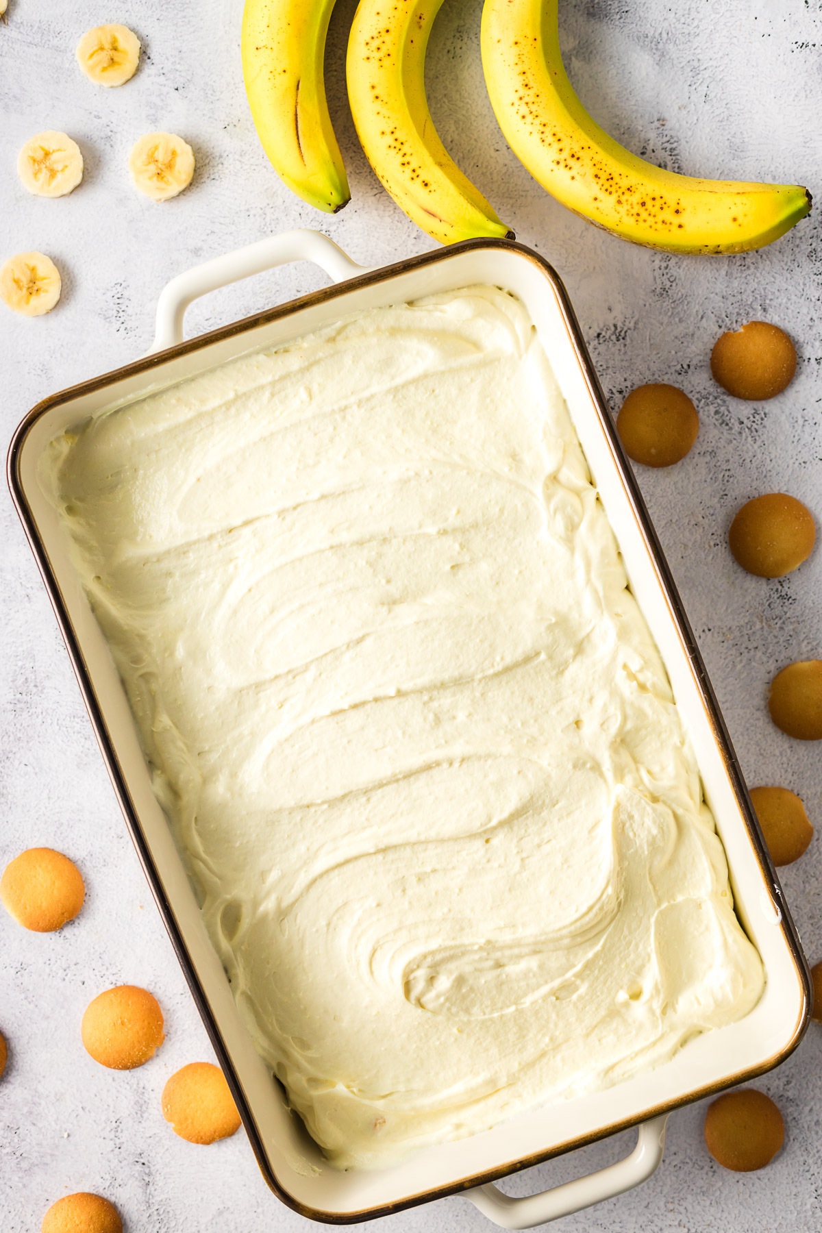 spreading combined pudding mixture over the layered cookies and bananas