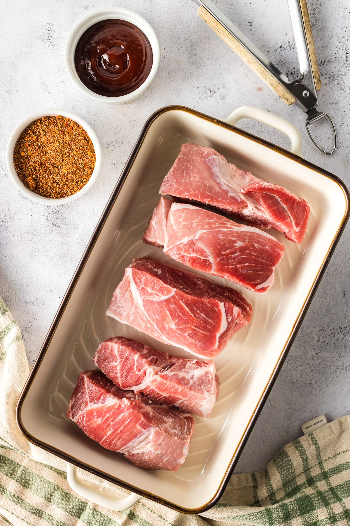 ingredients for boneless pork ribs, including country style pork ribs, dry rub seasoning, and bbq sauce