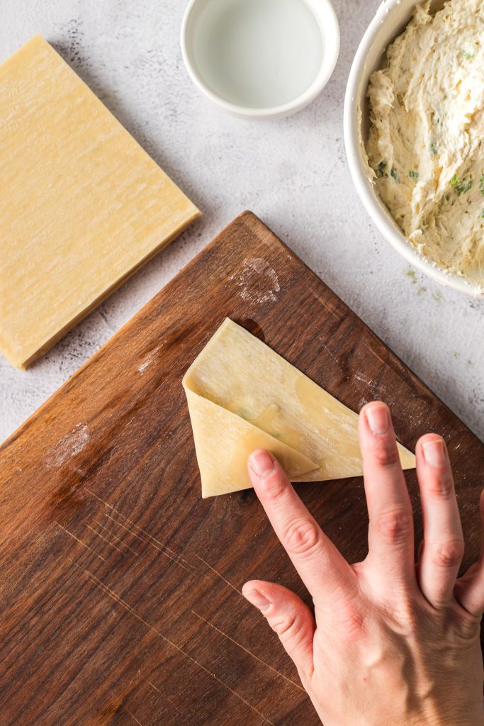 folding left corner of crab rangoon over center to create open envelope shape