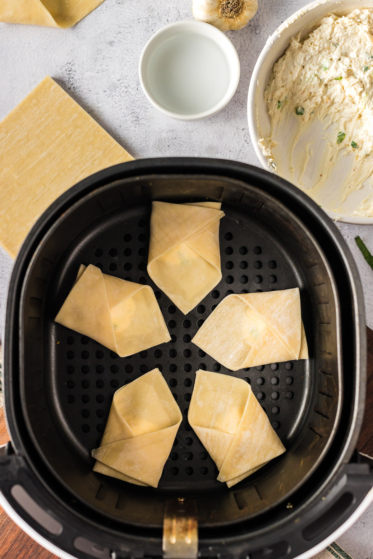 uncooked crab rangoon in air fryer basket