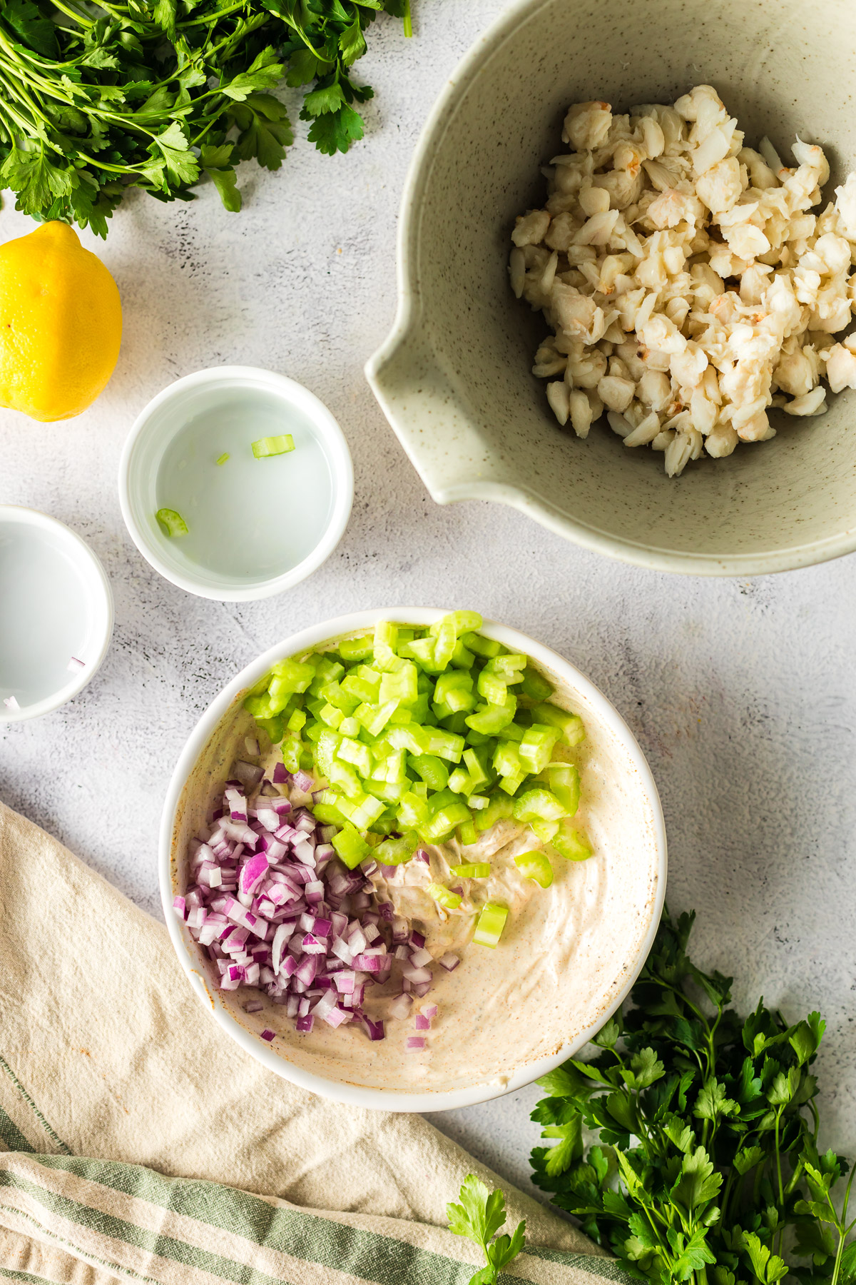 adding red onion and celery to crab salad dressing mixture