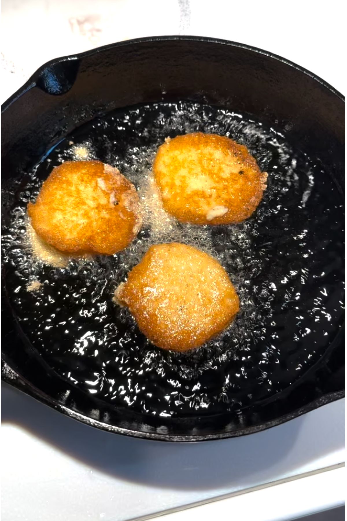 crispy hot water cornbread frying in a cast iron skillet