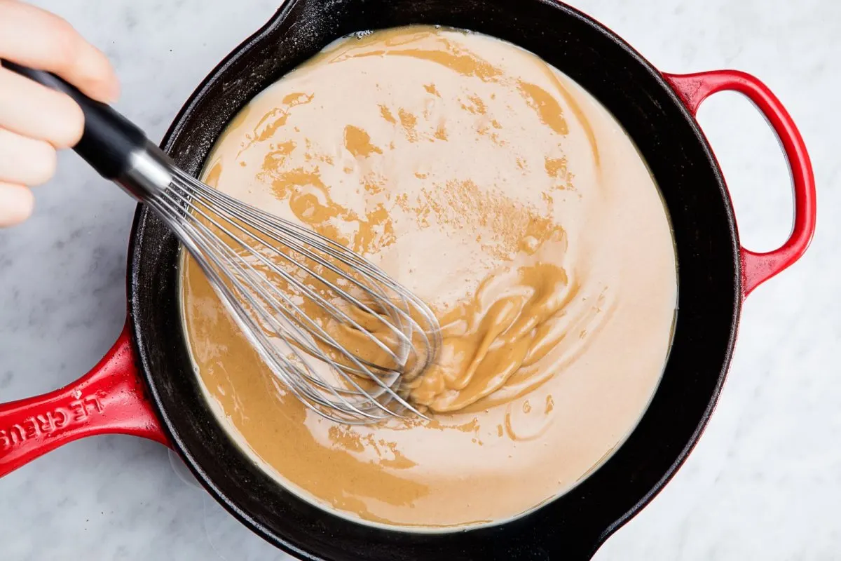 Cooking blond roux with whisk in red skillet