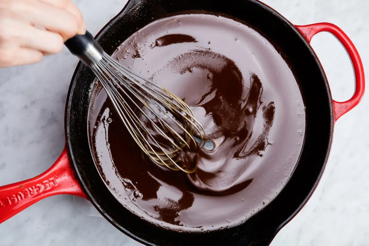 Cooking dark roux with whisk in red skillet