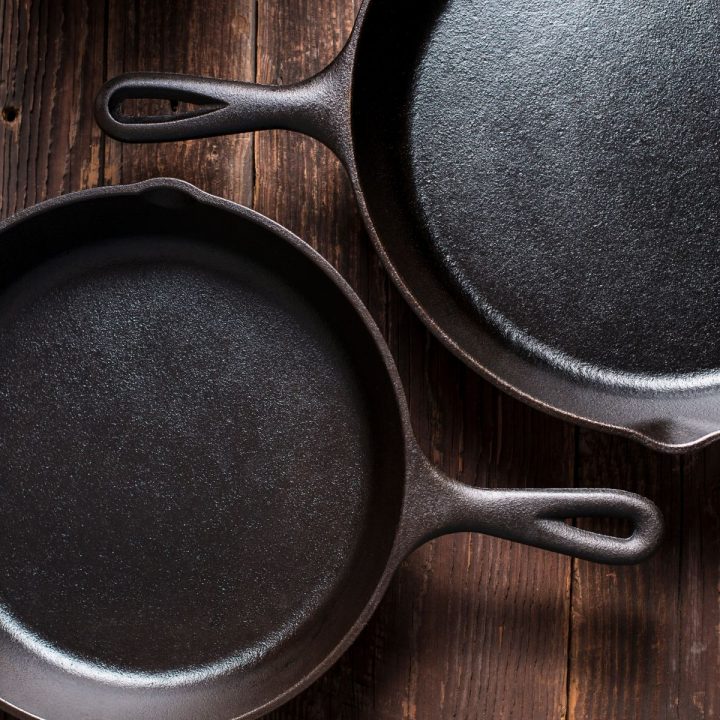 Two cast iron skillets on wooden background