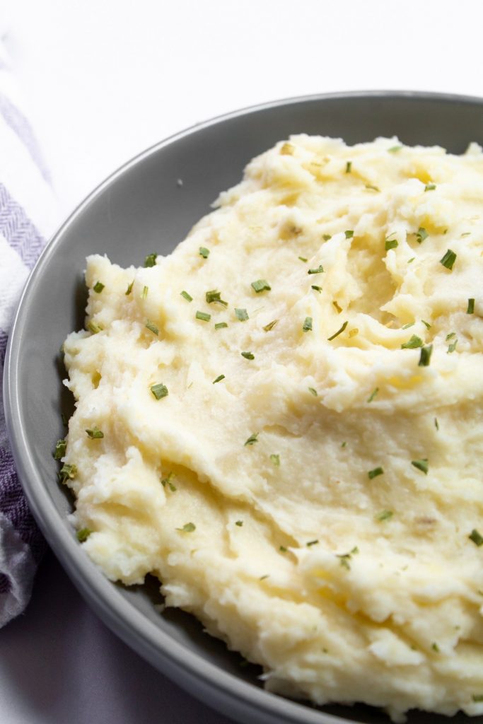close up of mashed potatoes in gray bowl with chive garnish