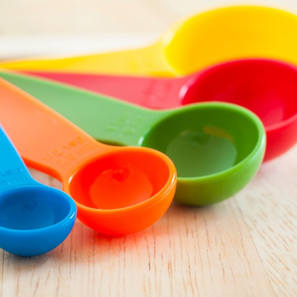Colorful measuring spoons on wooden board