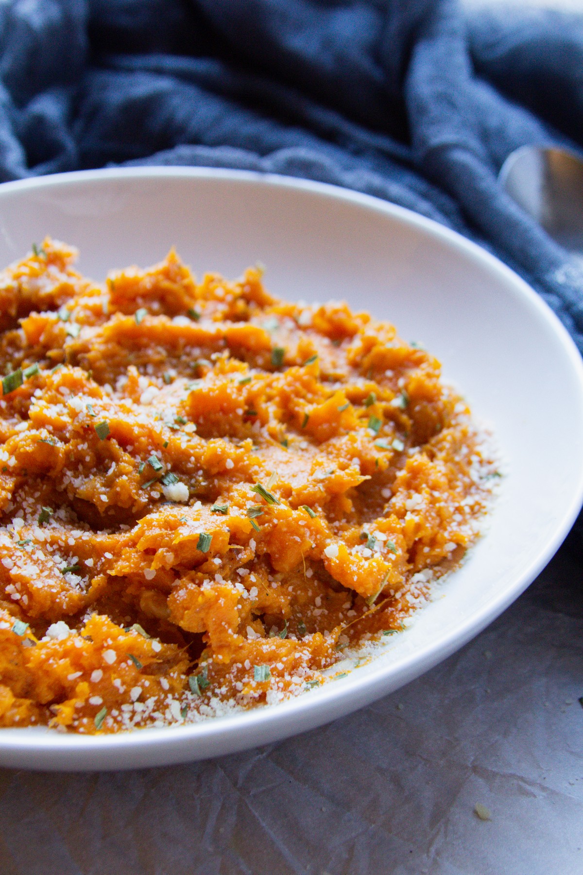 white bowl of mashed sweet potatoes with blue towel in background