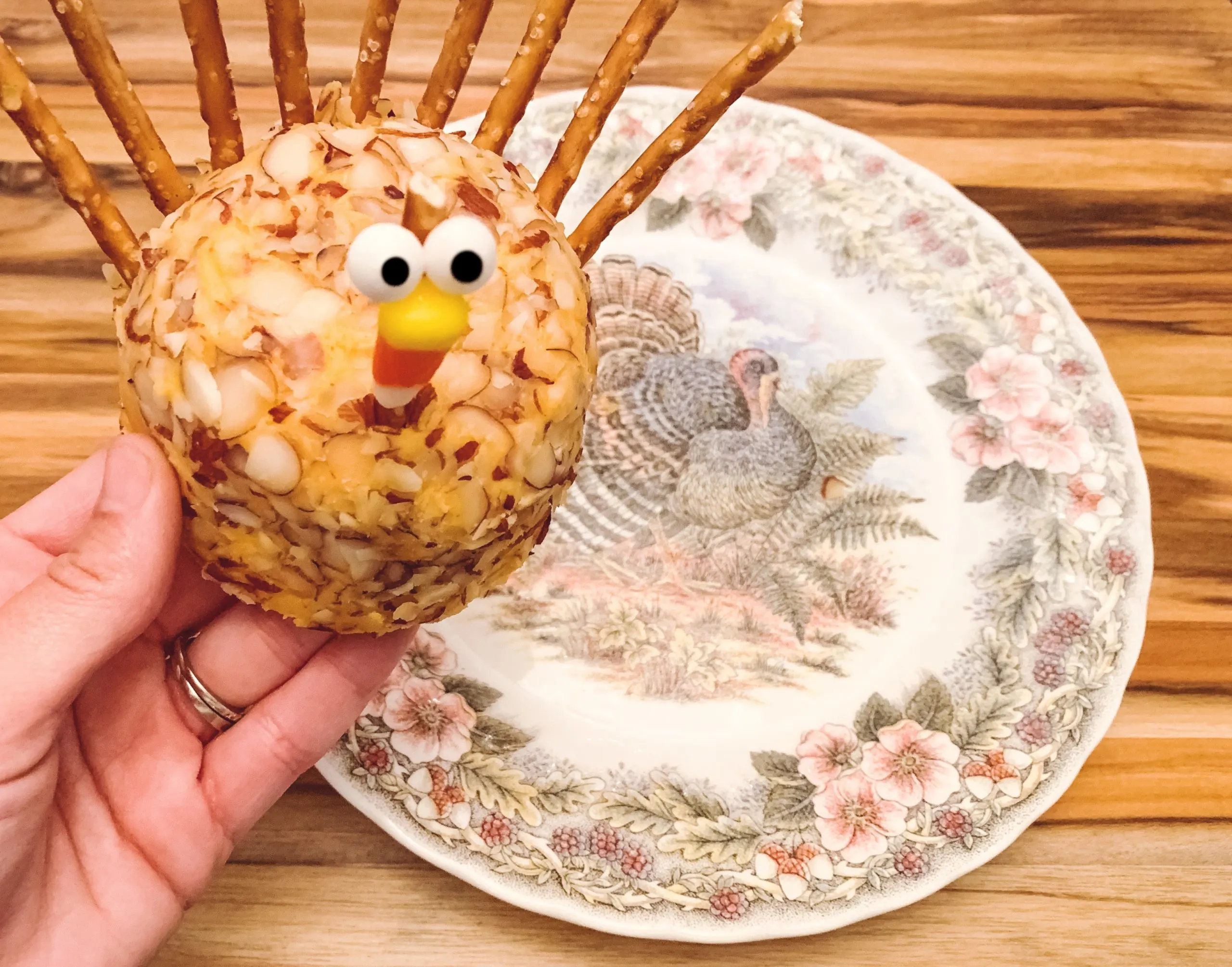 turkey cheese ball in hand with plate in background