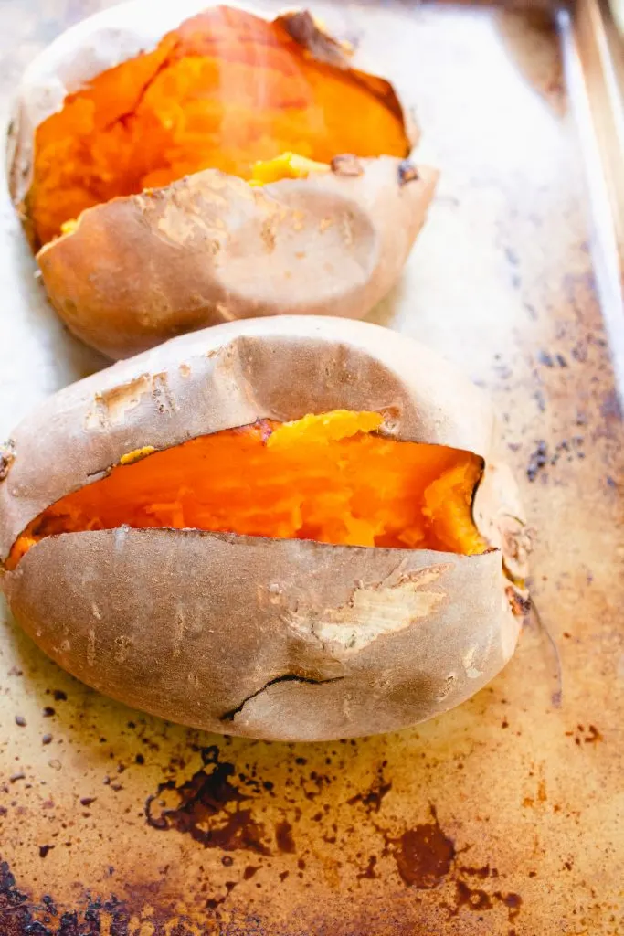 cooked sweet potato split open on on baking sheet 