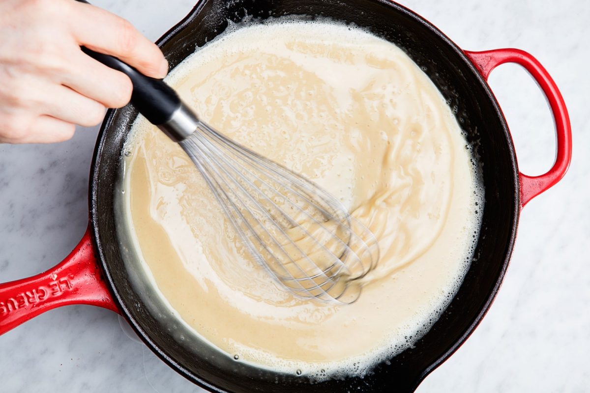 Cooking white roux with whisk in red skillet