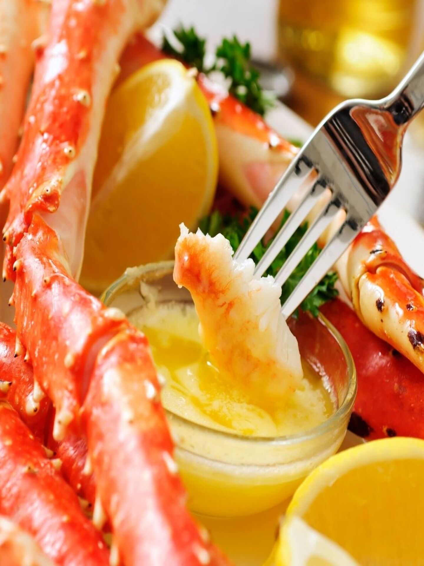 close view of baked crab legs being dipped in butter sauace